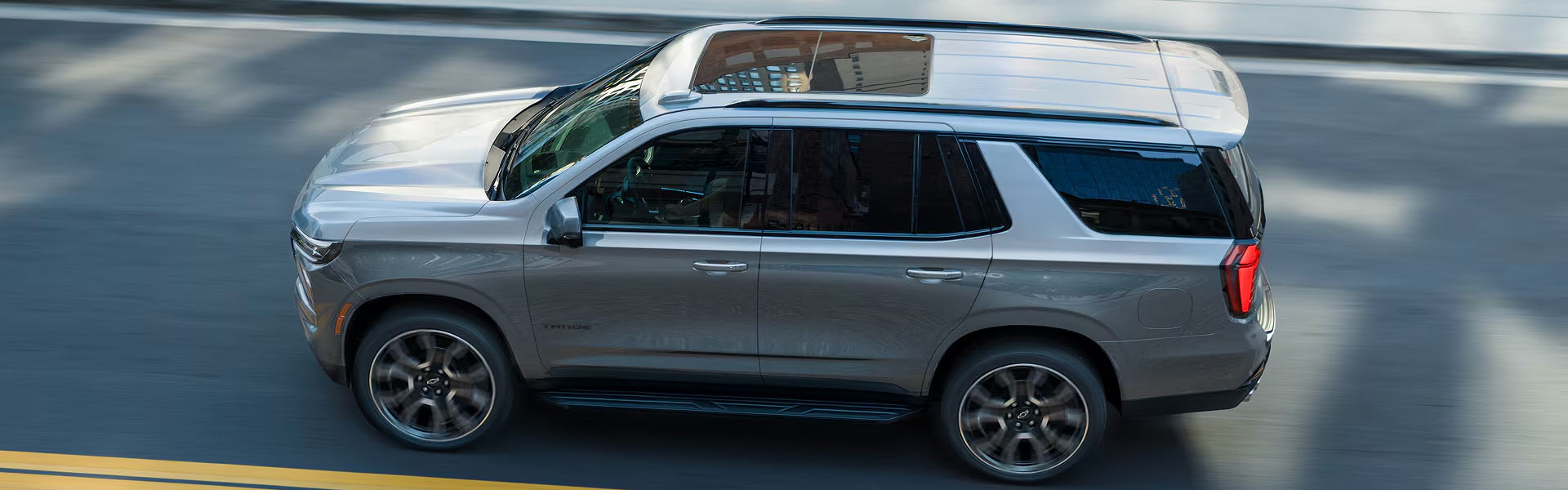 Gray Tahoe driving on city road.